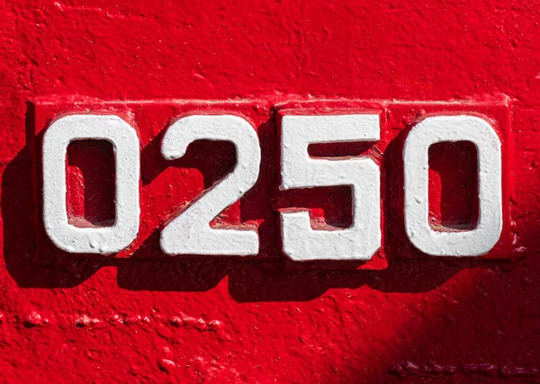 Weathered numbers zero, two, five, 0250, or 0, 2, 5 painted white on a piece of red metal. Abstarct numeral background for design.