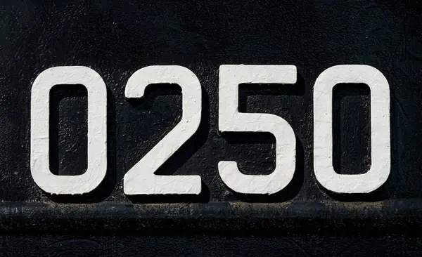 Weathered numbers zero, two, five, 0250, or 0, 2, 5 painted white on a piece of black metal. Abstarct numeral background for design.
