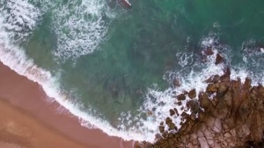 Karanlık bir denizde, okyanus yüzeyindeki kayalara akan dalgaları çarpan hava manzarası, kayalara çarpan inanılmaz deniz dalgaları, 4k 'lık okyanus manzaralı dron.