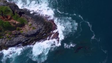 Karanlık bir denizde, okyanus yüzeyindeki kayalara akan dalgaları çarpan hava manzarası, kayalara çarpan inanılmaz deniz dalgaları, 4k 'lık okyanus manzaralı dron.
