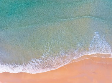 Sahildeki deniz yüzeyinin üst görüntüsü, yukarıdan çekilen açık deniz manzarası, inanılmaz doğa sahili arkaplanı, Güneş ışığını yansıtan Turkuaz su yüzeyi dalgaları.