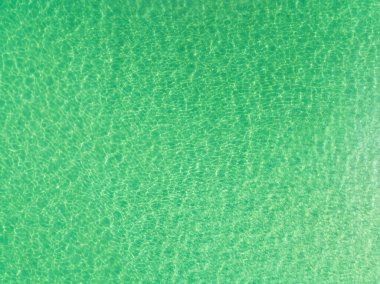 Yeşil deniz yüzeyinin en üst görüntüsü, yukarıdan çekilen açık deniz manzarası, Turkuaz su yüzeyinin inanılmaz arka planı, Güneş ışığını yansıtıyor.