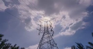 Yüksek voltajlı elektrik direkleri zaman ayarlı, yüksek voltajlı kule güneş ışığı parlaması mavi gökyüzü arka planında beyaz bulut, 4-k Timelapse alt görünümü elektrik direği