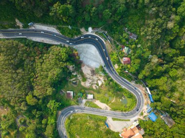 Aerial view top down drone shot above the winding mountain road between the trees rainforest,Phuket Thailand,in summer season weather, Car driving through the curve road