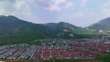 İnsansız hava aracı kamerası Hiperlapse Bulutları, güneşli bir günde küçük şehrin kenarında yeşil eteklerin üzerinde hareket eder.