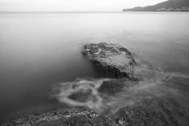 Deniz kıyısındaki kayaların üzerinde dalgalar siyah beyaz uzun pozlama fotoğraflarıyla