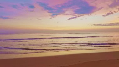 Kumsalda altın bir gün batımı, kumsalın üzerinde renkli ışık dalgalarına doğru yuvarlanan köpüklü dalgalar, kumsalda güzel bir gün batımı ya da deniz üzerinde gün doğumu, sahilde okyanus dalgaları, renkli gökyüzü.