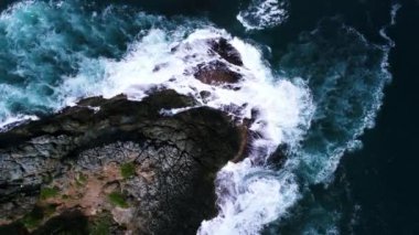 Karanlık bir denizde, deniz yüzeyindeki kayalara vuran dalgalar, çarpan inanılmaz deniz dalgaları.