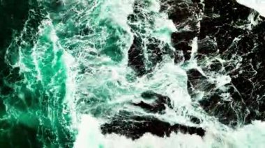 Karanlık bir denizde, deniz yüzeyindeki kayalara vuran dalgalar, çarpan inanılmaz deniz dalgaları.