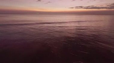 Renkli gün batımı ya da deniz yüzeyinde gün doğumu, açık denizin üzerinde uçan hava aracı.