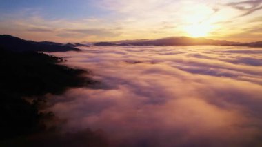 Gün doğumunda sislerin üzerinde uçan hava manzarası, gün doğumunda güzel bulutların güzel okyanusları, ufuk çizgisine kadar sonsuz bulutların üzerinde yükselen güneş.