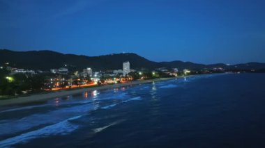 Karon şehrinin gece hava görüntüsü deniz yüzeyinin üzerinde güneş batıyor. Hava aracı Karon sahilinde, Phuket Tayland 'da uçuyor.