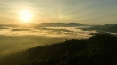 Gün doğumunda sislerin üzerinde uçan hava manzarası, gün doğumunda güzel bulutların güzel okyanusları, ufuk çizgisine kadar sonsuz bulutların üzerinde yükselen güneş.