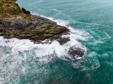 Deniz kıyısındaki kayalara çarpan dalgalar, arka plandaki deniz yüzeyi dalgaları
