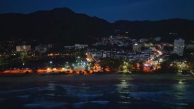 Karon şehrinin gece hava görüntüsü deniz yüzeyinin üzerinde güneş batıyor. Hava aracı Karon sahilinde, Phuket Tayland 'da uçuyor.