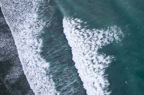 Amazing aerial view Top down of waves break on tropical sea Surfers with surfing boards Aerial drone view of sea waves on the beautiful sea surface ocean at Phuket Thailand.
