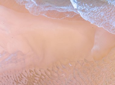 Kumlu sahile vuran dalgalar, arka planda deniz dalgaları