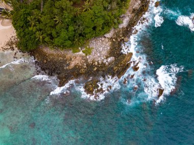 Deniz kıyısındaki kayalara çarpan dalgalar, arka plandaki deniz yüzeyi dalgaları