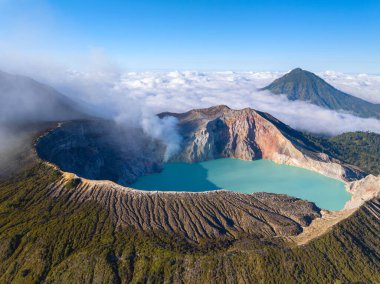 Kawah Ijen volkanındaki kayalıkların gündoğumunda turkuaz sülfür gölü manzarası. Doğu Java, Endonezya 'da büyüleyici doğa manzarası. Doğal manzara rengarenk gökyüzü arka planı.