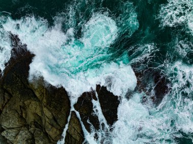 Kuş bakışı deniz kıyısı. Büyük dalgalar kayalıklara çarpıyor. Güneşli yaz arka planında güzel dalgalar deniz yüzeyinde inanılmaz deniz manzarası deniz manzarası manzarası