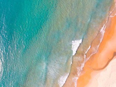 Kumlu sahile çarpan dalgaların hava görüntüsü, deniz yüzeyi okyanus dalgaları arka planı, plaj arka planı.