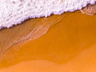 Kumlu sahile çarpan dalgaların hava görüntüsü, deniz yüzeyi okyanus dalgaları arka planı, plaj arka planı.