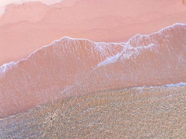 Deniz çarpan dalgaların havadan görünüşü kumsaldaki beyaz köpüklü dalgalar, en üstteki sahil yüzeyi, doğanın deniz kumsalı arka planı