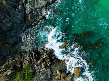 Kuş bakışı deniz kıyısı. Büyük dalgalar kayalıklara çarpıyor. Güneşli yaz arka planında güzel dalgalar deniz yüzeyinde inanılmaz deniz manzarası deniz manzarası manzarası
