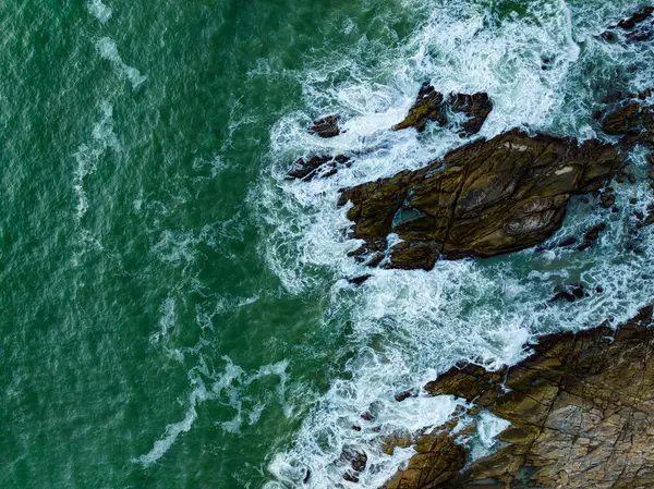 Kuş bakışı deniz kıyısı. Büyük dalgalar kayalıklara çarpıyor. Güneşli yaz arka planında güzel dalgalar deniz yüzeyinde inanılmaz deniz manzarası deniz manzarası manzarası