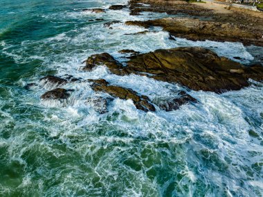 Kuş bakışı deniz kıyısı. Büyük dalgalar kayalıklara çarpıyor. Güneşli yaz arka planında güzel dalgalar deniz yüzeyinde inanılmaz deniz manzarası deniz manzarası manzarası
