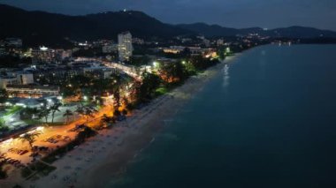 Karon şehrinin gece hava görüntüsü deniz yüzeyinin üzerinde güneş batıyor. Hava aracı Karon sahilinde, Phuket Tayland 'da uçuyor.