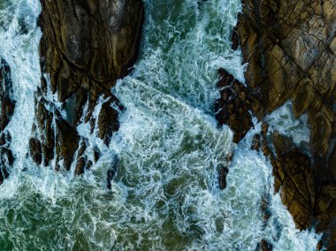 Kuş bakışı deniz kıyısı. Büyük dalgalar kayalıklara çarpıyor. Güneşli yaz arka planında güzel dalgalar deniz yüzeyinde inanılmaz deniz manzarası deniz manzarası manzarası