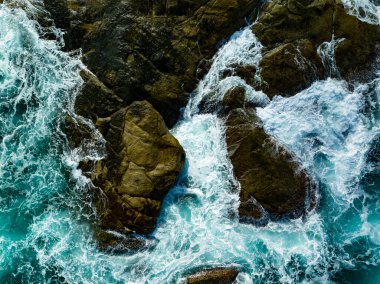 Kuş bakışı deniz kıyısı. Büyük dalgalar kayalıklara çarpıyor. Güneşli yaz arka planında güzel dalgalar deniz yüzeyinde inanılmaz deniz manzarası deniz manzarası manzarası