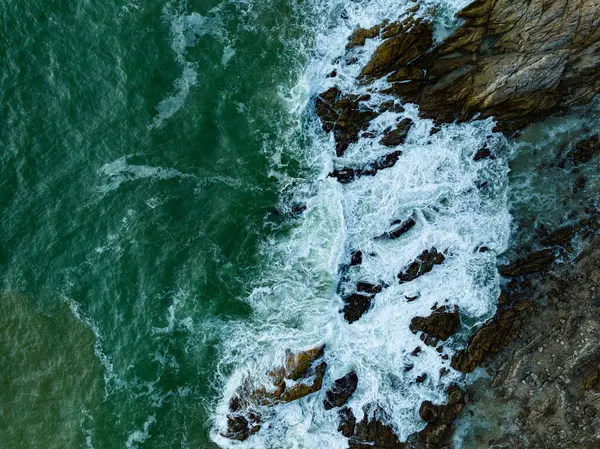 Kuş bakışı deniz kıyısı. Büyük dalgalar kayalıklara çarpıyor. Güneşli yaz arka planında güzel dalgalar deniz yüzeyinde inanılmaz deniz manzarası deniz manzarası manzarası