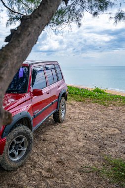 Phuket Tayland 5 Aralık 2023, 4x4 Kırmızı araba Suzuki Vitara 1993 toprak yolda, Phuket Tayland 'da güneşli gökyüzünde güzel deniz manzarası.