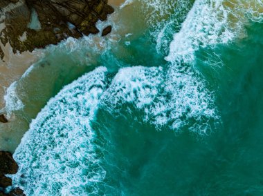 Kuş bakışı deniz kıyısı. Büyük dalgalar kayalıklara çarpıyor. Güneşli yaz arka planında güzel dalgalar deniz yüzeyinde inanılmaz deniz manzarası deniz manzarası manzarası
