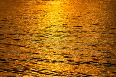 Dalgaların tam çerçeve arka planı deniz suyu dalgalanması ve altın güneş batımı ışığını yansıtması, deniz yüzeyinin soyut arkaplanı