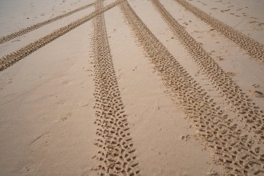 4x4 lastik izleri kum dokusu arka planında çapraz lastik izleri.