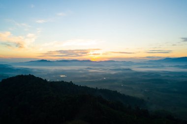 Güneşin doğuşu ya da batışı dağların tepelerinde sisle kaplı, hava manzaralı insansız hava aracı güzel renkli bir arka plan çekti.