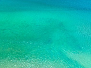 Mavi deniz yüzeyinin arka planının havadan görünüşü, suya yansıyan güneş ışığı, uçan dron görüntüsü Phuket Adası Tayland 'daki güneşli tropikal okyanusta su yüzeyi dokusu dalgaları.