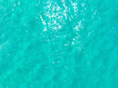 Mavi deniz yüzeyinin arka planının havadan görünüşü, suya yansıyan güneş ışığı, uçan dron görüntüsü Phuket Adası Tayland 'daki güneşli tropikal okyanusta su yüzeyi dokusu dalgaları.