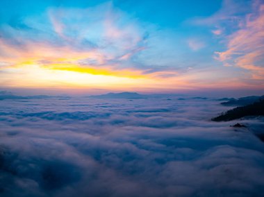 Güneşin dağların tepelerinde doğuşu sisle kaplı, hava manzaralı insansız hava aracı güzel bir gökyüzü çekti. Renkli, aydınlık bir arka plan.