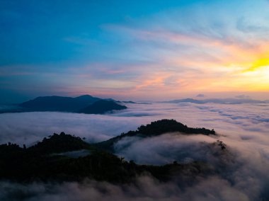 Güneşin dağların tepelerinde doğuşu sisle kaplı, hava manzaralı insansız hava aracı güzel bir gökyüzü çekti. Renkli, aydınlık bir arka plan.