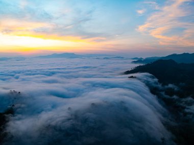 Güneşin dağların tepelerinde doğuşu sisle kaplı, hava manzaralı insansız hava aracı güzel bir gökyüzü çekti. Renkli, aydınlık bir arka plan.