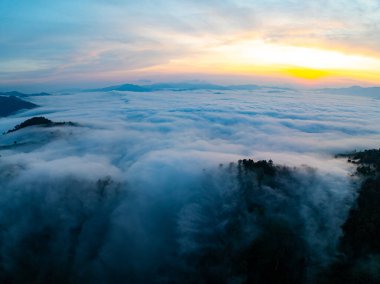 Güneşin dağların tepelerinde doğuşu sisle kaplı, hava manzaralı insansız hava aracı güzel bir gökyüzü çekti. Renkli, aydınlık bir arka plan.