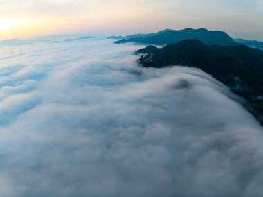 Güneşin dağların tepelerinde doğuşu sisle kaplı, hava manzaralı insansız hava aracı güzel bir gökyüzü çekti. Renkli, aydınlık bir arka plan.