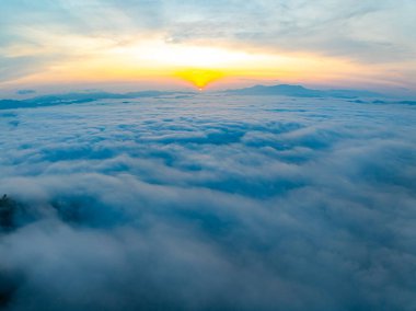 Güneşin dağların tepelerinde doğuşu sisle kaplı, hava manzaralı insansız hava aracı güzel bir gökyüzü çekti. Renkli, aydınlık bir arka plan.