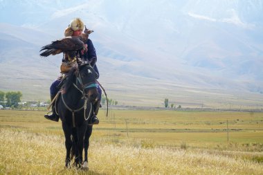 Kyrgyz nomad rider holding an eagle on a hand and sitting on a horse clipart