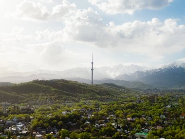 Güneşli bir bahar günü, arka planda karlı dağlarla birlikte televizyon kulesiyle Almaty şehrinin havadan görünüşü