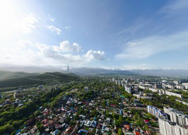 Güneşli bir bahar günü, arka planda karlı dağlarla birlikte televizyon kulesiyle Almaty şehrinin havadan görünüşü
